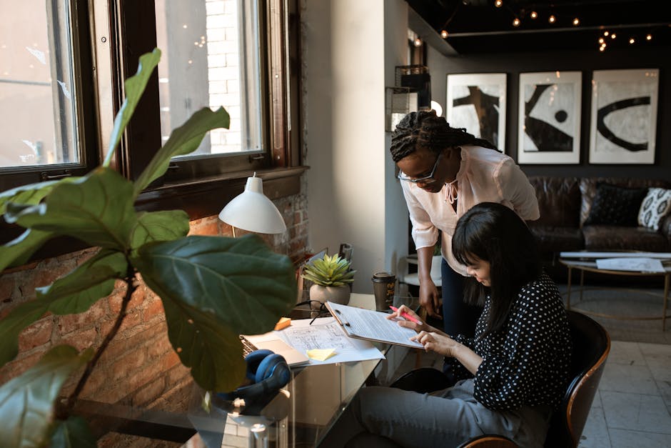 Two colleagues collaborate in a stylish, plant-filled workspace with natural light.