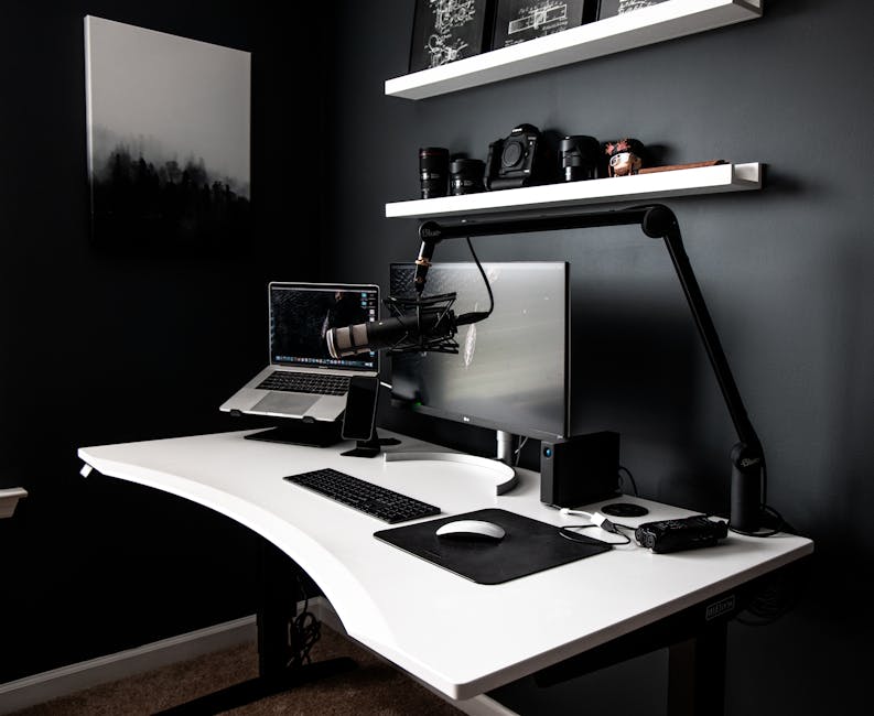 Contemporary style workspace with netbook near computer and microphone on white table in room with dark walls