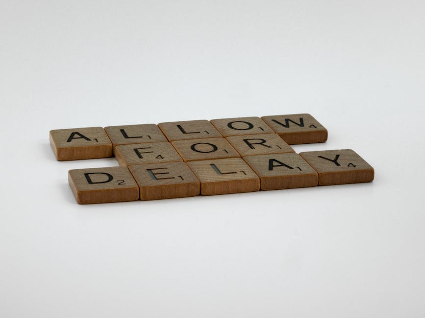 Wooden Scrabble tiles arranged on a white surface spelling 'Allow for Delay'.