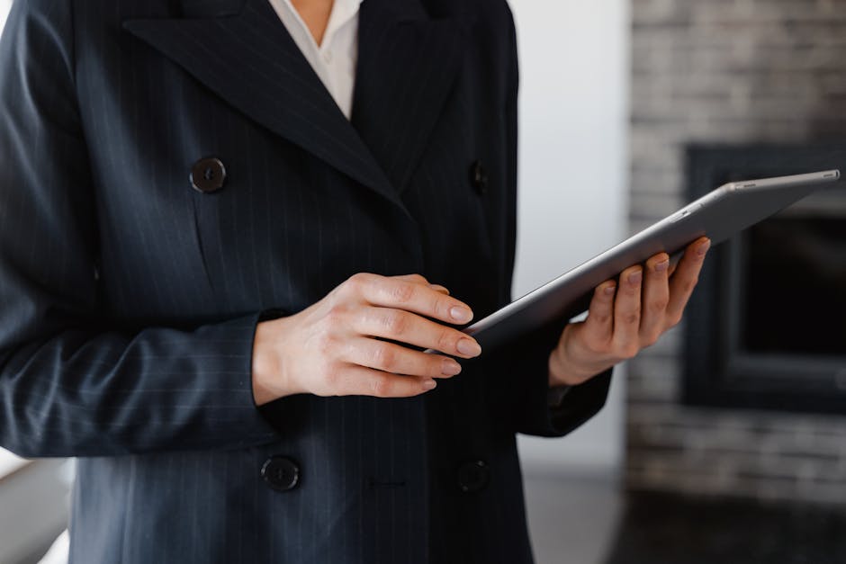 Close-up of a woman in a blazer using a digital tablet indoors.