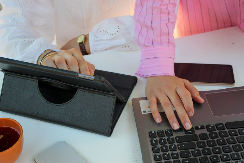Office scene showing teamwork using a laptop, tablet, and smartphone.
