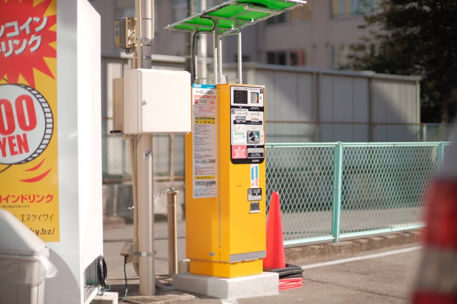 Yellow parking meter in city street with sunlight and urban surroundings.