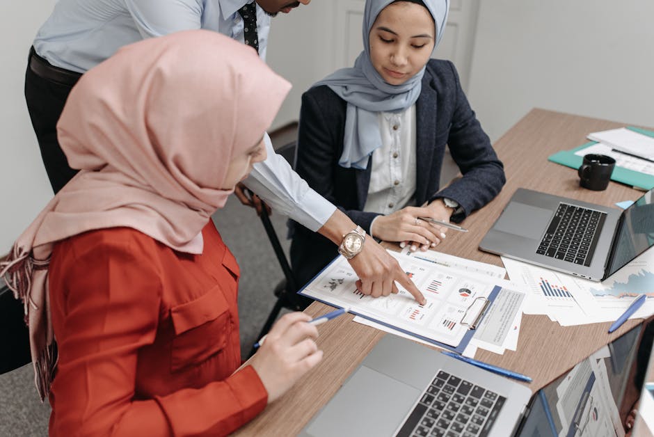 Professional team of Muslim women and colleague reviewing documents and data in an office meeting.
