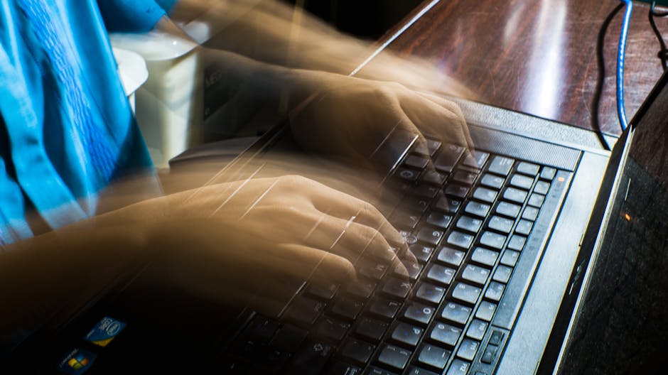 Blurred hands typing fast on a laptop, emphasizing speed and technology.
