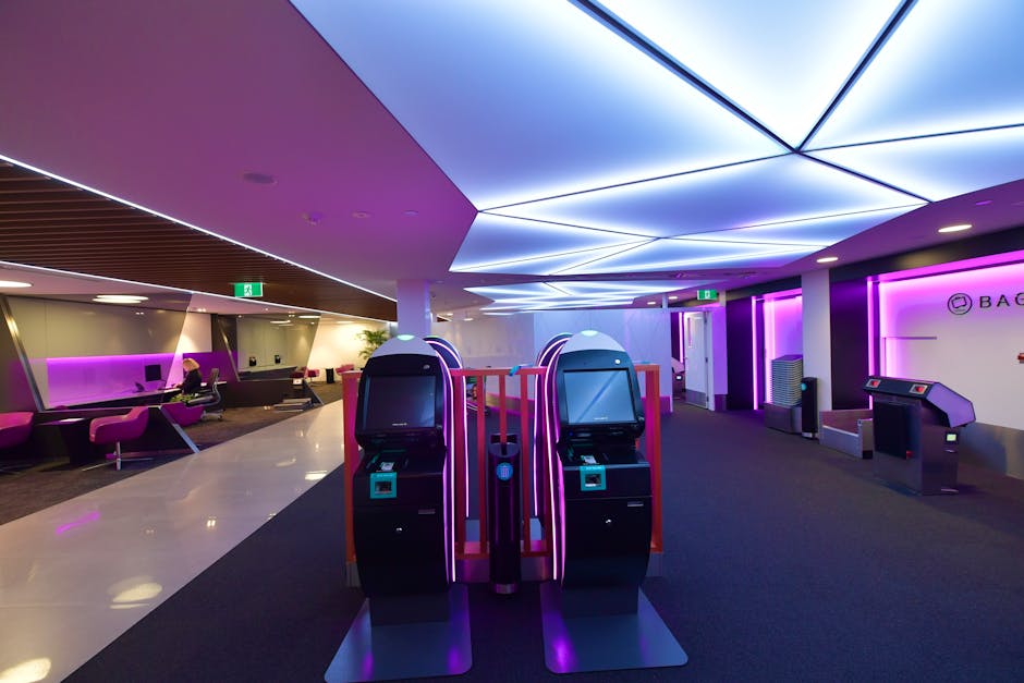 Stylish airport lounge featuring automated check-in machines and vibrant lighting.