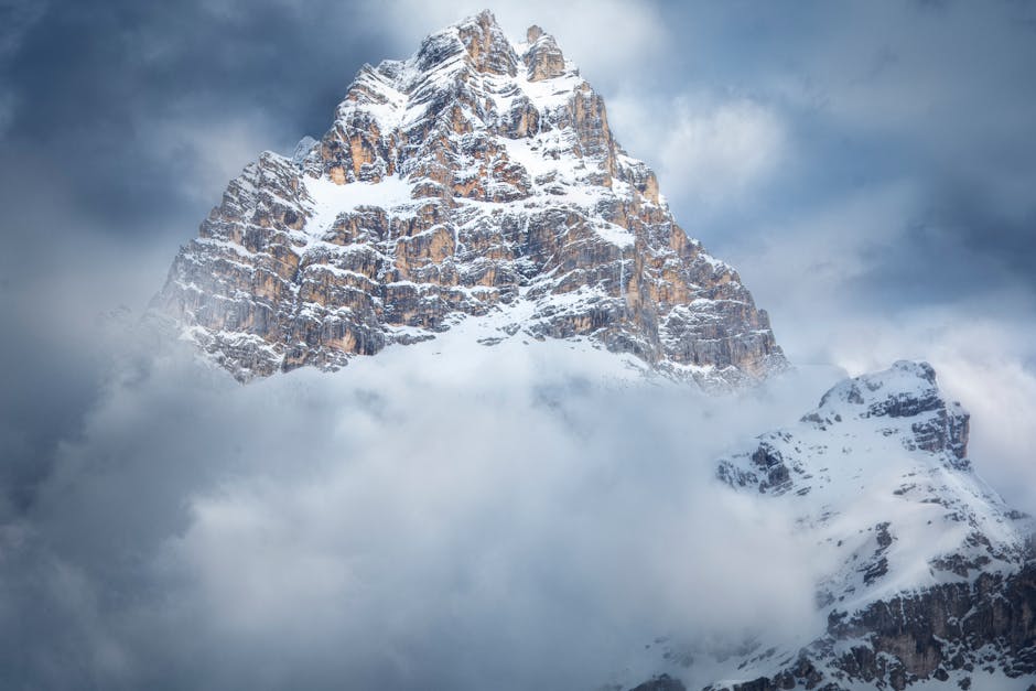 Majestic snow-covered peak in Cortina d'Ampezzo, Italy, surrounded by clouds.
