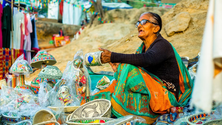 Elderly woman selling colorful traditional handicrafts at an outdoor market.