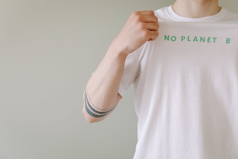 Close-up of a person showcasing a T-shirt with a 'No Planet B' environmental message.