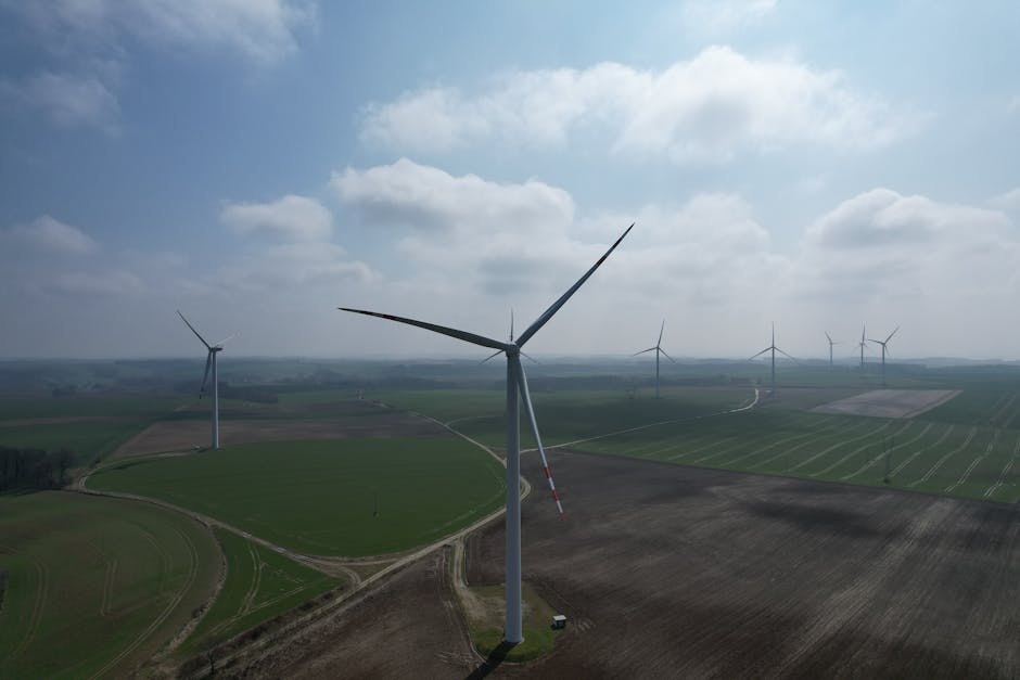A breathtaking aerial view of wind turbines amidst vast green fields, showcasing renewable energy potential.