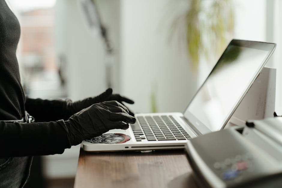 Tattoo artist wearing gloves works on a laptop in a modern studio setting.