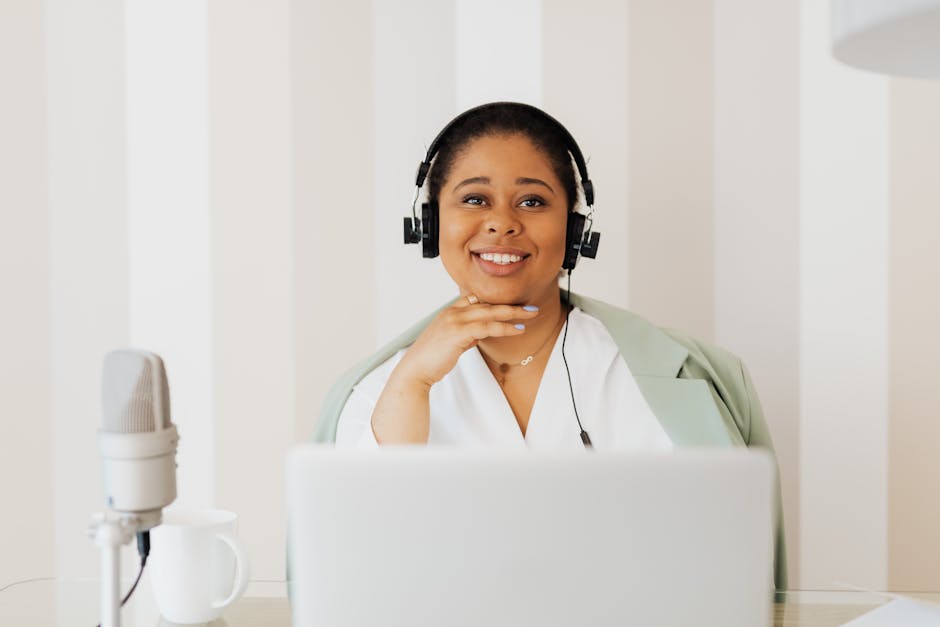 Smiling woman engaged in remote work with headphones and microphone setup.
