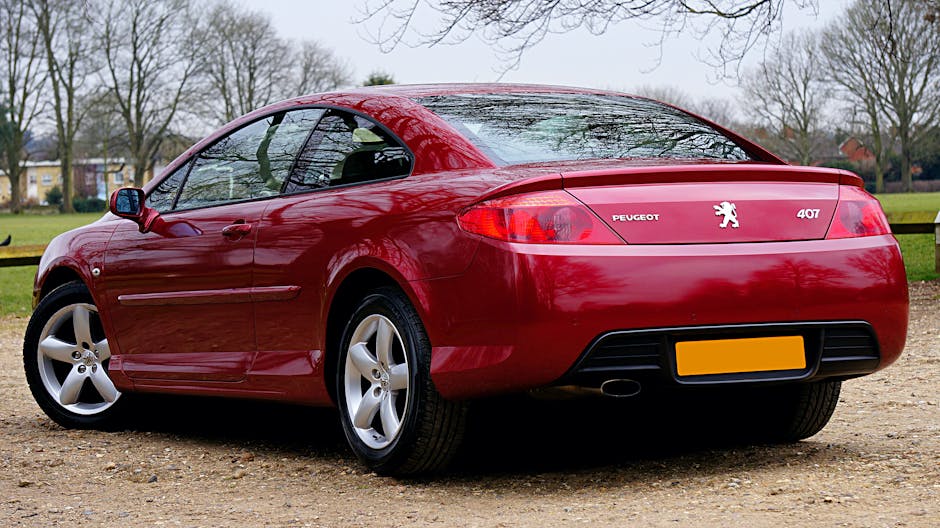 A luxurious red Peugeot 407 coupe parked outdoors in a scenic UK landscape. Perfect for auto enthusiasts.