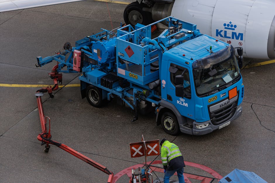 Ground crew at work refueling a KLM airplane with specialized equipment at an airport apron.