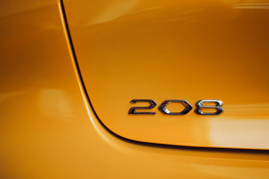 Glossy silver emblem on a vibrant yellow car showcasing the number 208.