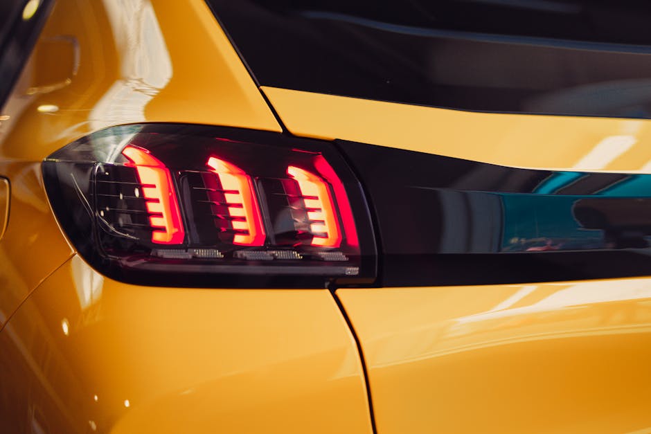 Bright and glossy close-up of a modern car taillight in a showroom setting.