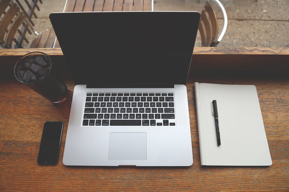A minimalist workspace featuring a laptop, notebook, and phone for efficient remote work.