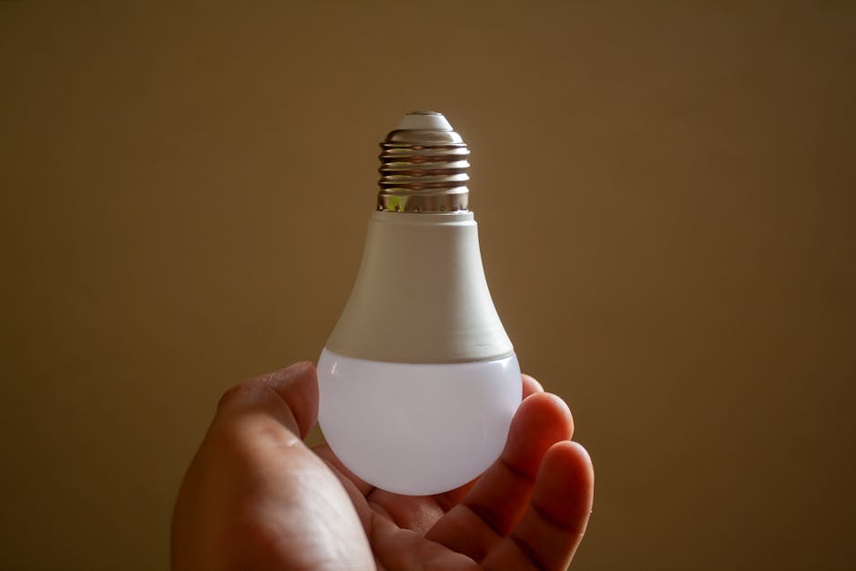 Close-up of a hand holding an energy-efficient LED bulb, emphasizing sustainability and innovation.