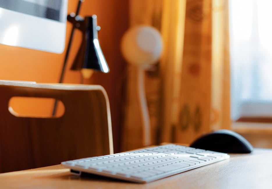 Close-up of a clean desk setup featuring a wireless keyboard and mouse on a wooden table.