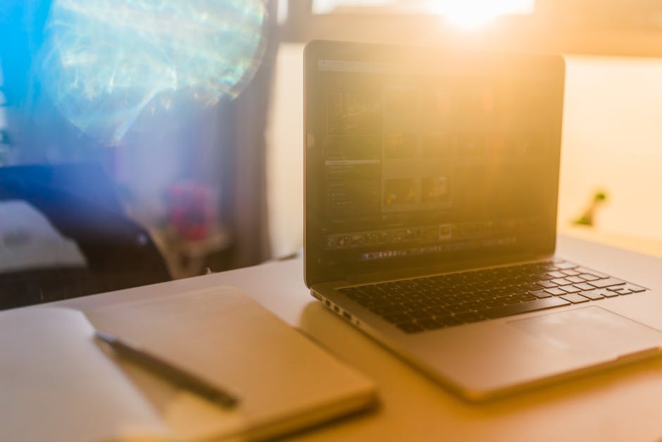 A laptop and notebook on a sunlit desk create a warm workspace vibe.