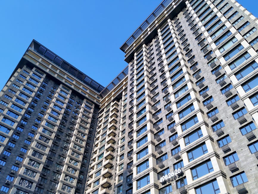 Low angle view of contemporary apartment buildings with glass windows against a clear blue sky.