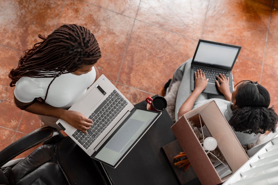 Two women using laptops in a bright workspace, focusing on collaboration and productivity.