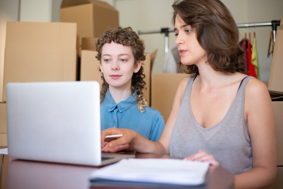Two women collaborating on a project using a laptop in an office environment.