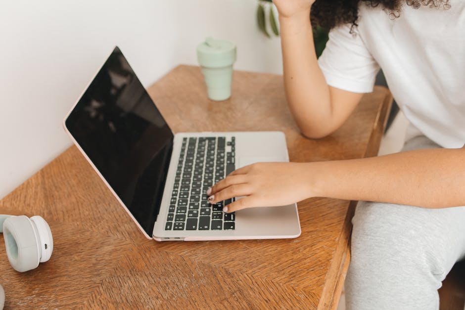 Focused woman working remotely from home with a laptop on a wooden desk.