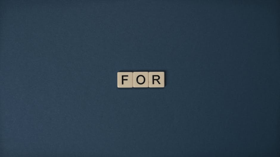 Artistic display of Scrabble tiles spelling the word 'For' on a dark background.