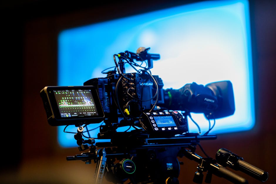 Close-up of a professional video camera setup in a studio environment with vibrant lighting.