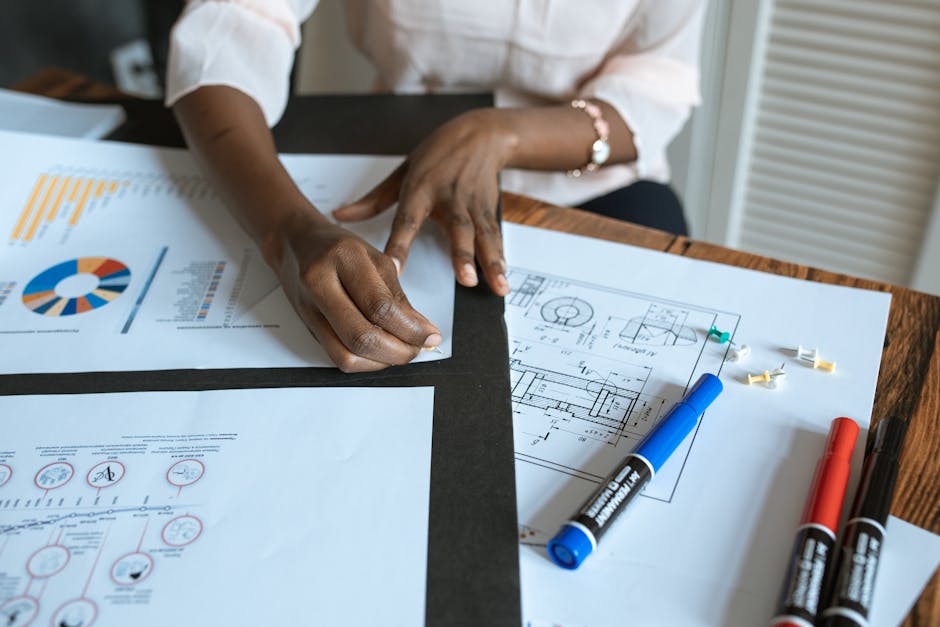 An adult working on business charts and design blueprints in an office setting.