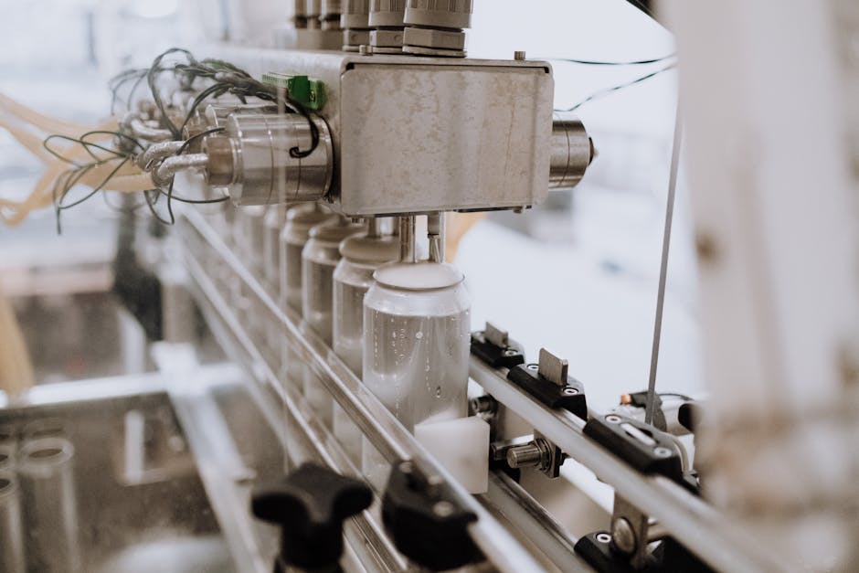 Close-up of an automated can filling machine in a beverage production line.